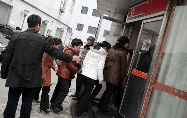 A group of North Korean women in the streets of Dandong, China in March 2023 being overseen by a North Korean government minder.